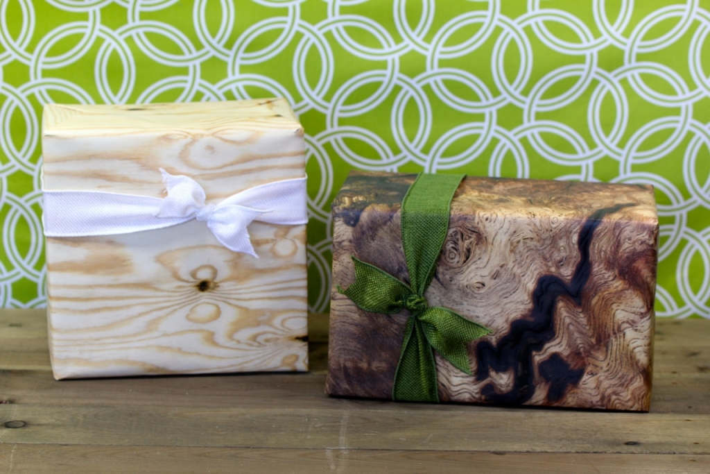 Two gift boxes wrapped with ribbon, one white and one green, resting on a patterned green and white surface, evoking thoughtful presentation.